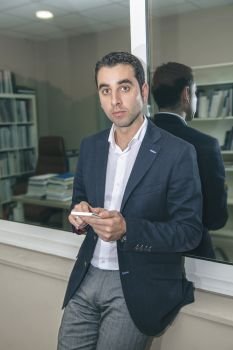 Portrait of handsome businessman looking at camera while holding smartphone. Businessman looking at camera while holding smartphone