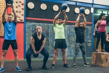Group of athletes exercising with kettlebells. Athletes exercising with kettlebells indoors