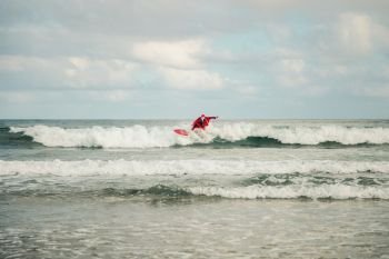 One young man surfer dressed as Santa Claus on the beach surfing