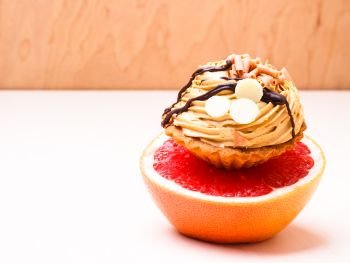 Concept of making choice: healthy low-calorie or unhealthy high-calorie food, slimming or fattening. Grapefruit and cake cupcake.