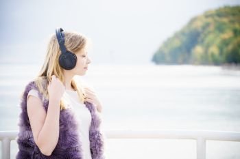 Relaxed woman listening to music while being outdoor. Teenage female wearing headphones having great time chilling outside.. Woman wearing headphones outdoor
