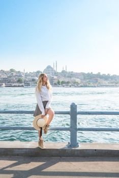 Attractive young beautiful girl stands over Galata Bridge and enjoys view of bosphorus in Istanbul,Turkey.Traveler concept