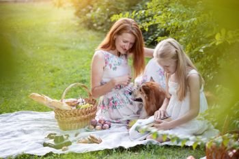Summer - happy family at a picnic.  Mom, daughter and dog corgi at a picnic 
