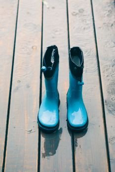 Blue wellies standing on a wooden porch while raining