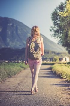 Young girl in jumpsuit with backpack is taking a walk, summer time