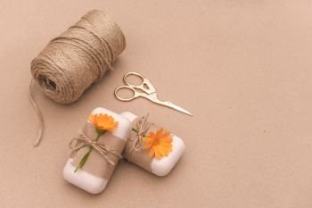 Handmade natural soap decorated with craft paper, orange calendula flowers, skein of twine and scissors . Organic cosmetics concept. Copy space for text Template for yuor design.. Handmade natural soap decorated with craft paper, orange calendula flowers, skein of twine and scissors . Organic cosmetics concept. Copy space for text Template for yuor design