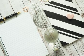 Spring book, black and white notebook, pen, tranportir, paper clips and glass globe on a gray wooden background. Work at home. School.
