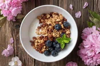 Breakfast cereals with yogurt and blueberries, with pink kwanzan cherry blossoms