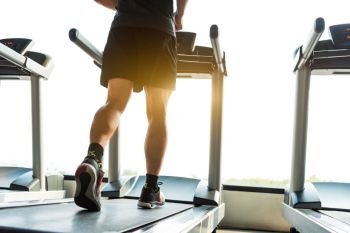 Legs of sportsman running on treadmill in fitness gym center. Sport and Healthy lifestyle concept. People workout and exercise activity. Back view or rear view
