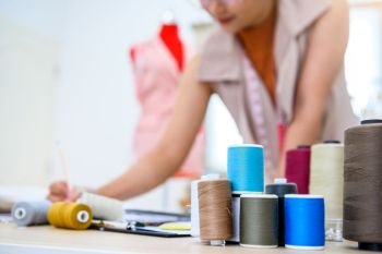 Closeup of colorful thread with fashion designer background in workshop studio. Stylish fashionista woman creating new cloth design collection. Tailoring and sewing People lifestyle and occupation