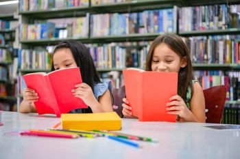 Happiness two cute diversity girls reading book in school library funny. People lifestyles and friend Education and friendship concept. Leisure child and kids group activity