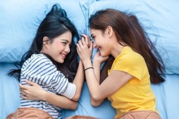 Two Asian womens looking at each others when lying on bed. Lifestyles and lovers concept. Happiness life and relax concept. Homosexual life theme. LGBT pride and lesbian couples theme.