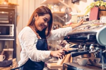 Professional female barista hand making cup of coffee with coffee maker machine in restaurant pub or coffee shop. People and lifestyles. Business food and drink concept.  Happy shop owner entrepreneur