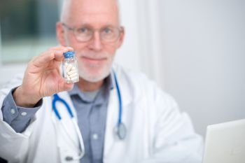 a mature doctor with pill in hospital