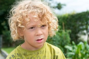 Portrait of a little boy with blond and curly hair