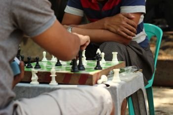 two 2 Myanmar men playing an informal, competitive game of chess on the street during a lunch break in Yangon, Myanmar, Southeast Asia