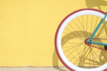 Close-up detail of cogwheel on a vintage bicycle against a yellow wall