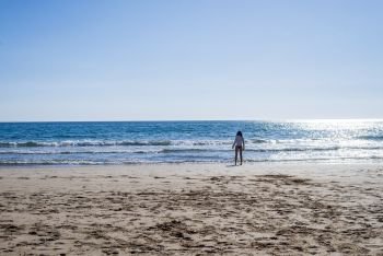 Rear view of lonely woman standing at seashore wearing panties in sunny day