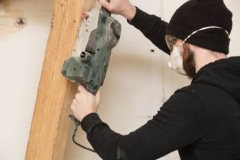 handyman works with detail sander , renovating a home building concept. handyman works with detail sander , renovating a home