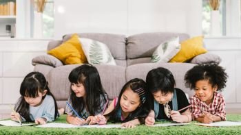 Group of five multi-ethnic young cute preschool kids, boy and girls happy studying or drawing together at home or school. Children education, youth culture lifestyle, or fun learning activity concept