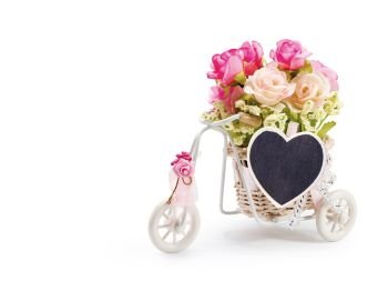 Rose flowers in bicycle basket with heart clothes pin on white background