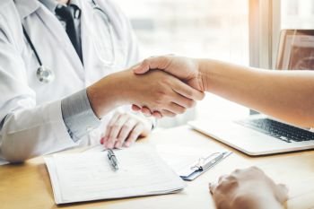Confident Doctor shaking hands with patients talk in the hospital office