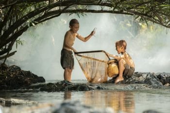Asia children glad fisherman on river stream / The boy friend happy funny laughing fishing with net and fish in hand at countryside of living life kids rural people