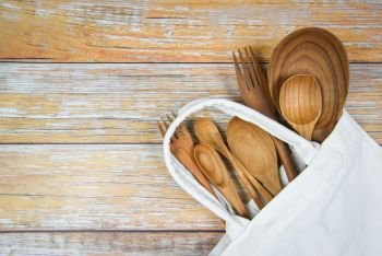 Natural kitchen tools wood products / Kitchen utensils background with spoon fork chopsticks plate cutting board object and cloth bag , top view on the table utensil wooden concept