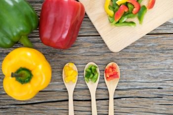 Colorful bell peppers and kitchen utensil on white wooden table. Top view