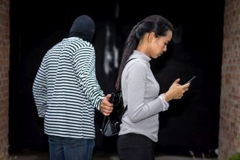 robber pulling the woman bag while her using smartphone
