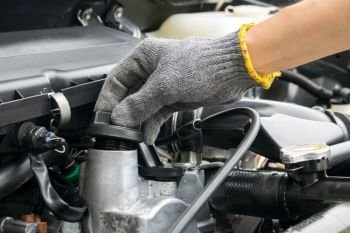A mechanic is opening the oil cap from a car engine.