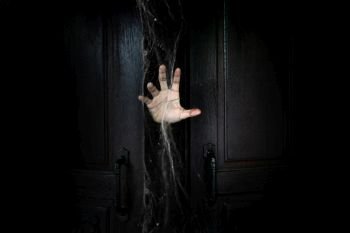The hand of the man holding the stick from the wooden door from the inside of the dark room
