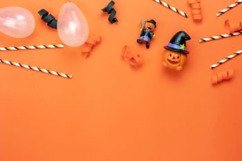 Table top view aerial image of decoration Happy Halloween day background concept.Flat lay accessory essential object to party the pumpkin cartoon doll & balloon with confetti and straw on orange paper
