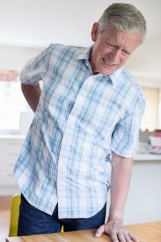 Mature Man Suffering From Backache Whilst Getting Out Of Chair At Home