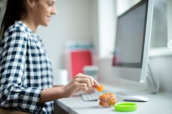 Female Worker In Office Having Healthy Snack Of Dried Apricots At Desk