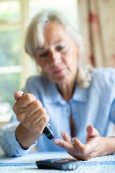 Senior Diabetic Woman Testing Blood Sugar Level At Home