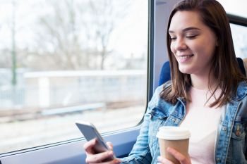 Young Woman Texting On Mobile Phone During Train Journey