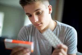 Teenage Boy With Mental Health Problems Taking Medication At Home