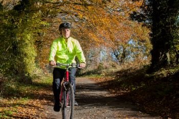 Mature Man Cycling Along Autumn Country Road