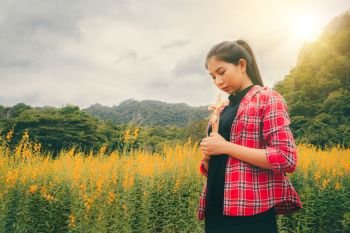Young beautiful woman praying on nature background. Hope and faith concept.