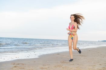 Attractive woman runner runs on tropical sand beach in summer. Healthy lifestyle and running sport concept.. Attractive woman runs on sand beach in summer.