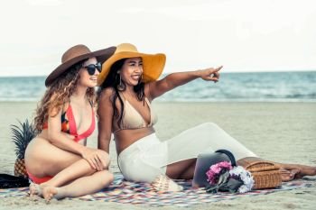 Happy women in bikinis sitting together on tropical sand beach in summer vacation. Travel lifestyle.. Happy women sitting on sand beach in summer.