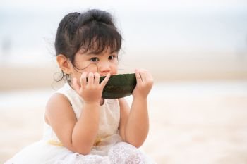 Adorable kid eating watermelon on the tropical sand beach in summer.. Adorable kid eating watermelon on the beach.