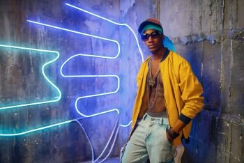 Black rapper in underpass neon light on background. Rap performer in club with grunge walls, underground music. Black rapper in underpass neon light on background