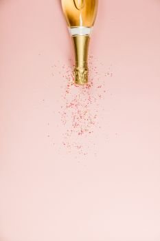 Flat lay of Celebration. Champagne bottle with sprinkles. Flat lay of Celebration. Champagne bottle with sprinkles on pink background.