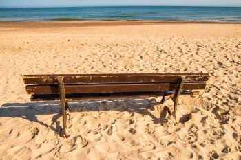 bench on a lonesome beach of the Baltic Sea with blue sky 