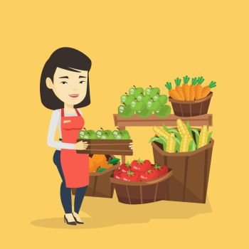 Asian worker of grocery store standing in front of section with vegetables and fruits. Female worker of grocery store holding a box with apples. Vector flat design illustration. Square layout.. Supermarket worker with box full of apples.
