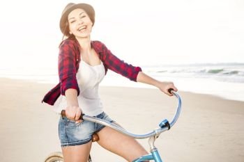An attractive young woman riding her bicycle on the beach