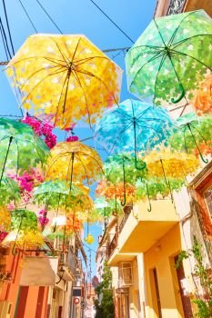 Street decorated with umbrellas of different colours in Aegina town on summer sunny day, Aegina island, Greece