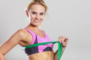 Weight loss, slim body, healthy lifestyle concept. Fit fitness woman in sport bra measuring her chest breasts with green measure tape. Fit woman measuring her chest breasts with tape measure